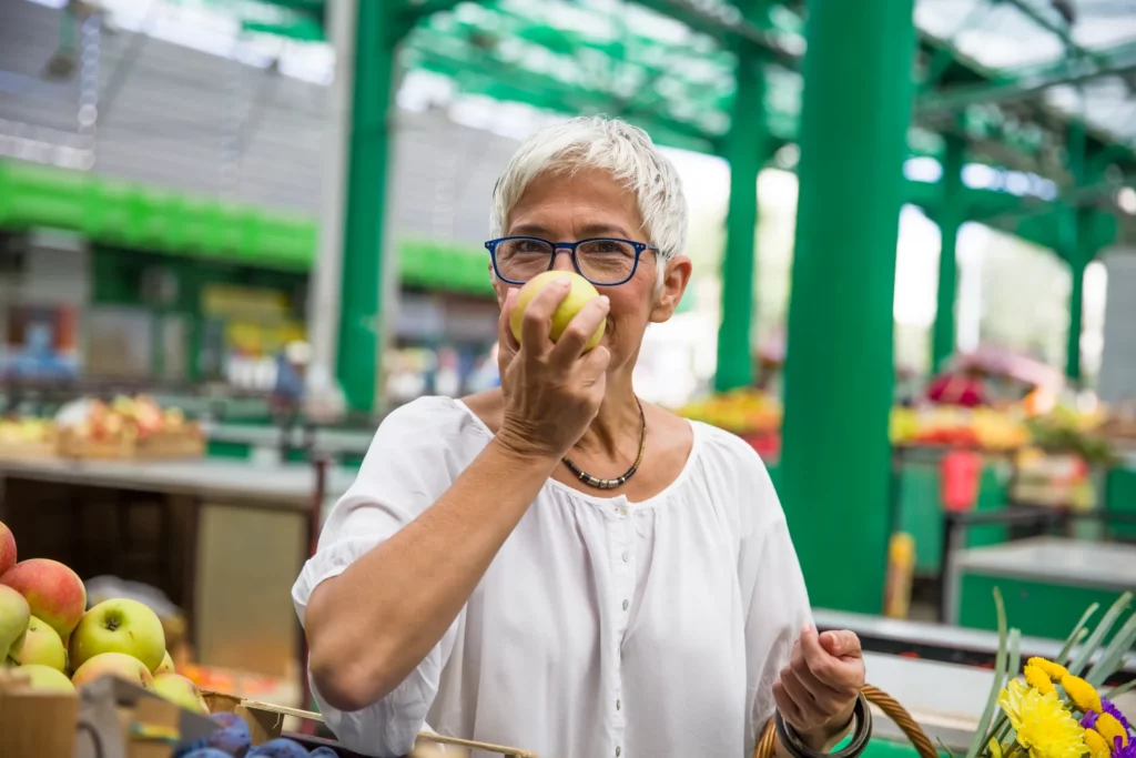 senior woman buying apples on market 2023 11 27 04 53 35 utc 1